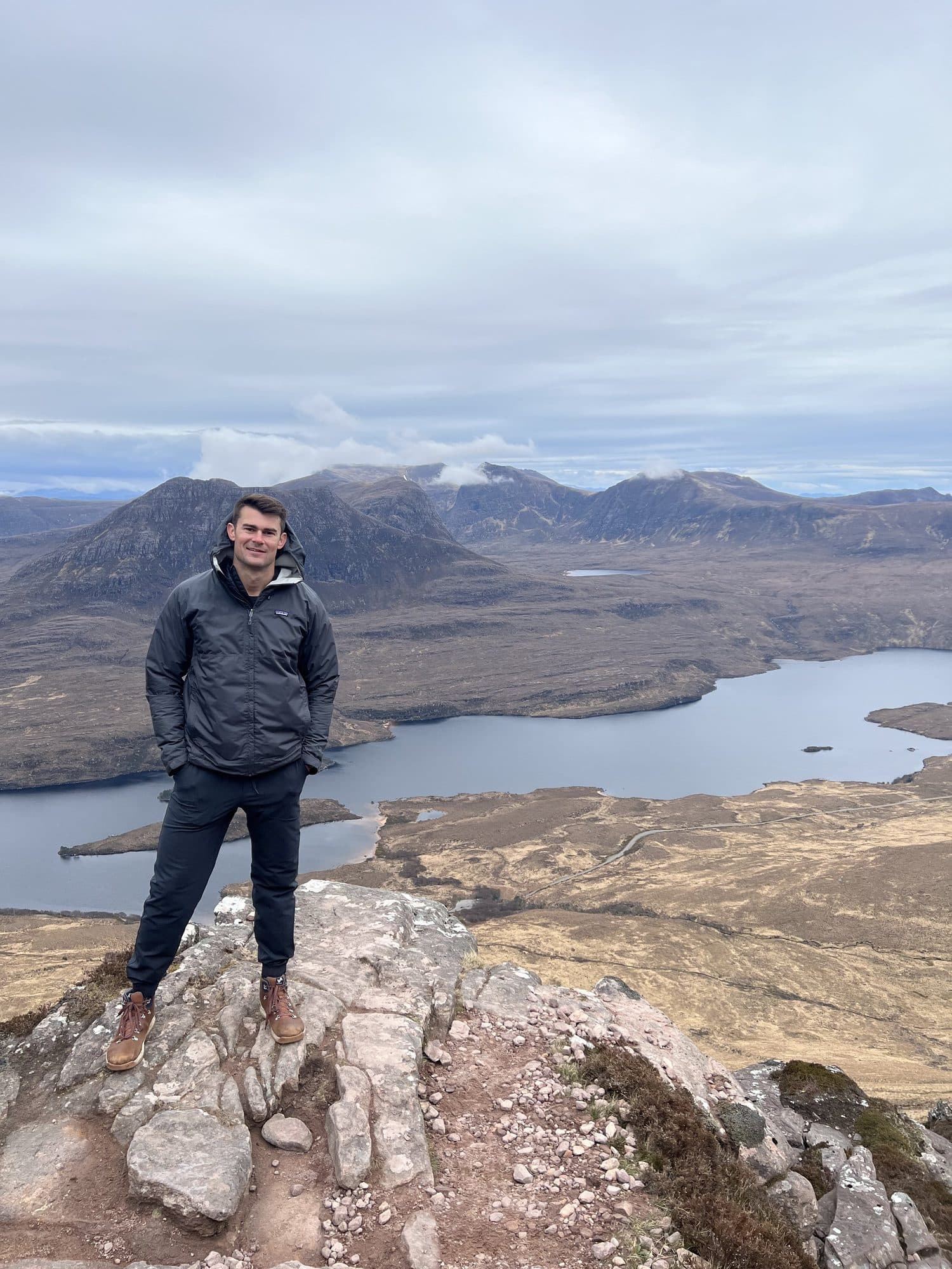 Billy on the summit of Stac Pollaidh above a loch