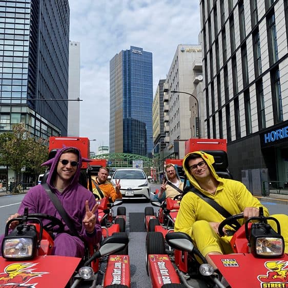 Two friends in costume driving go-karts through Tokyo
